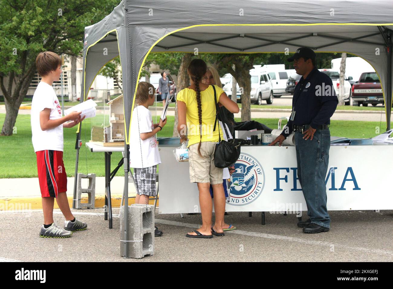 Flooding - Bismarck, N. D. , August 6, 2011   FEMA Mitigation Liason Emiliano Flores, looks on as Community Relations Specialist Hilda Rodriguez speaks to interested community members at the FEMA information Booth at the base of the North Dakota State Capitol Building in Bismarck during a yearly festival called the 'Capitol a'Fair. ' FEMA utilized their booth at the fair to promote mitigation ideas to the community as well as providing information on programs available to those affected by the flood. Robert Kaufmann/FEMA. North Dakota Flooding. Photographs Relating to Disasters and Emergency M Stock Photo