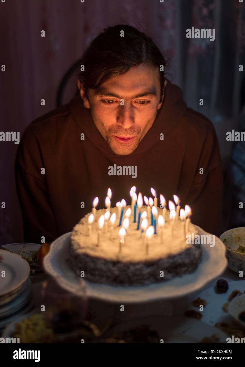 young man blow out the candles on the cake celebrating Birthday party