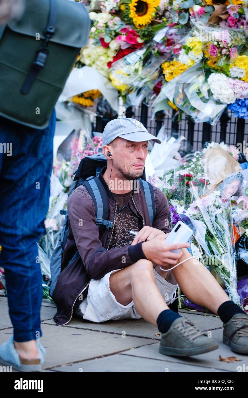 A man sits on the pavement crying expressing an outpouring of grief to the death of Her Majesty The Queen Elizebeth II photographed at Buckingham Palace And The Queen Victoria Memorial, London on Friday 9 September 2022 . Picture by Julie Edwards. Stock Photo