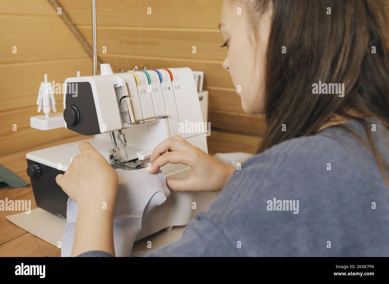 A woman designer works on an overlock sewing machine on tailoring. Small tailoring business