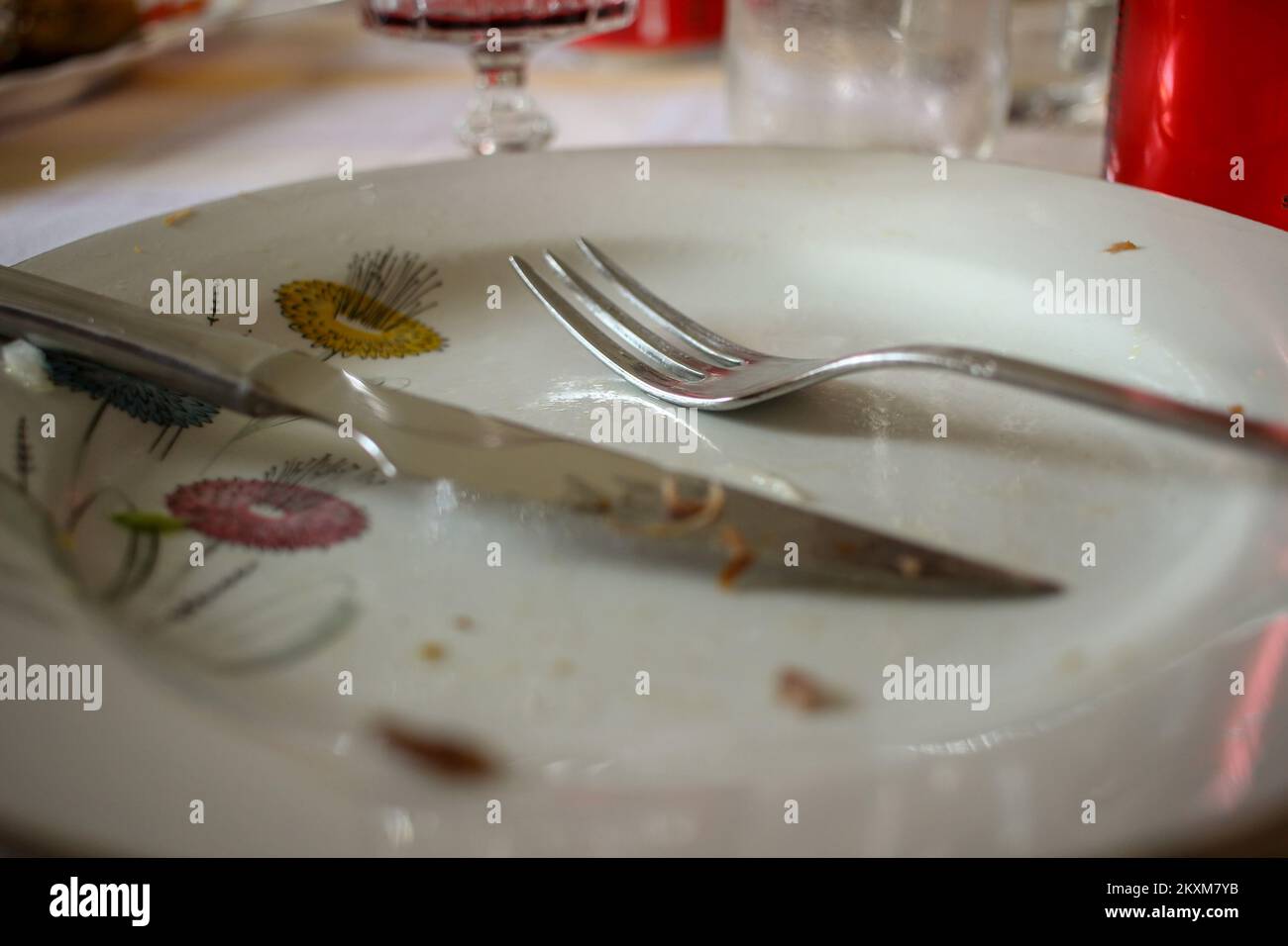 a fork and a knife remain in the plate after having some meat for lunch Stock Photo