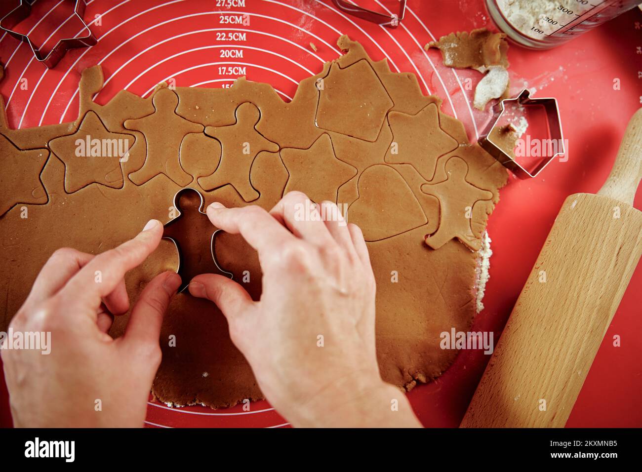Woman preparing gingerbread cookies at kitchen. Female hands cutting ginger dough with cutter to making cookies for winter holidays Stock Photo