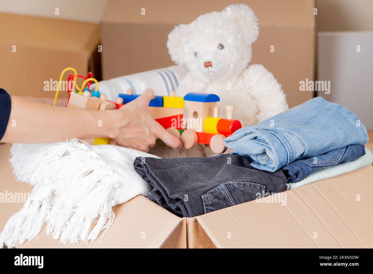 Woman hands collecting donation box with clothes, bed linen, kid toys