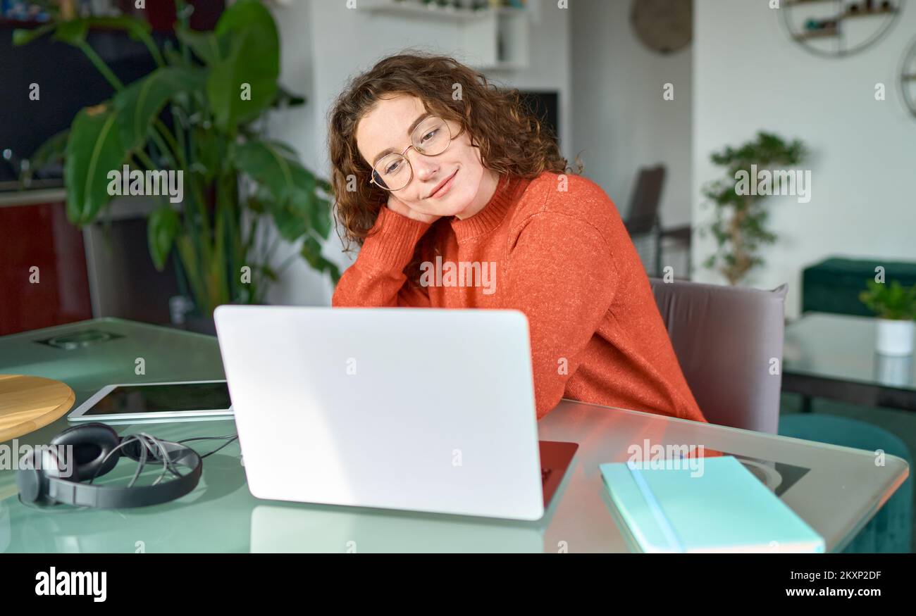 Young smiling woman student using laptop elearning or working at home. Stock Photo