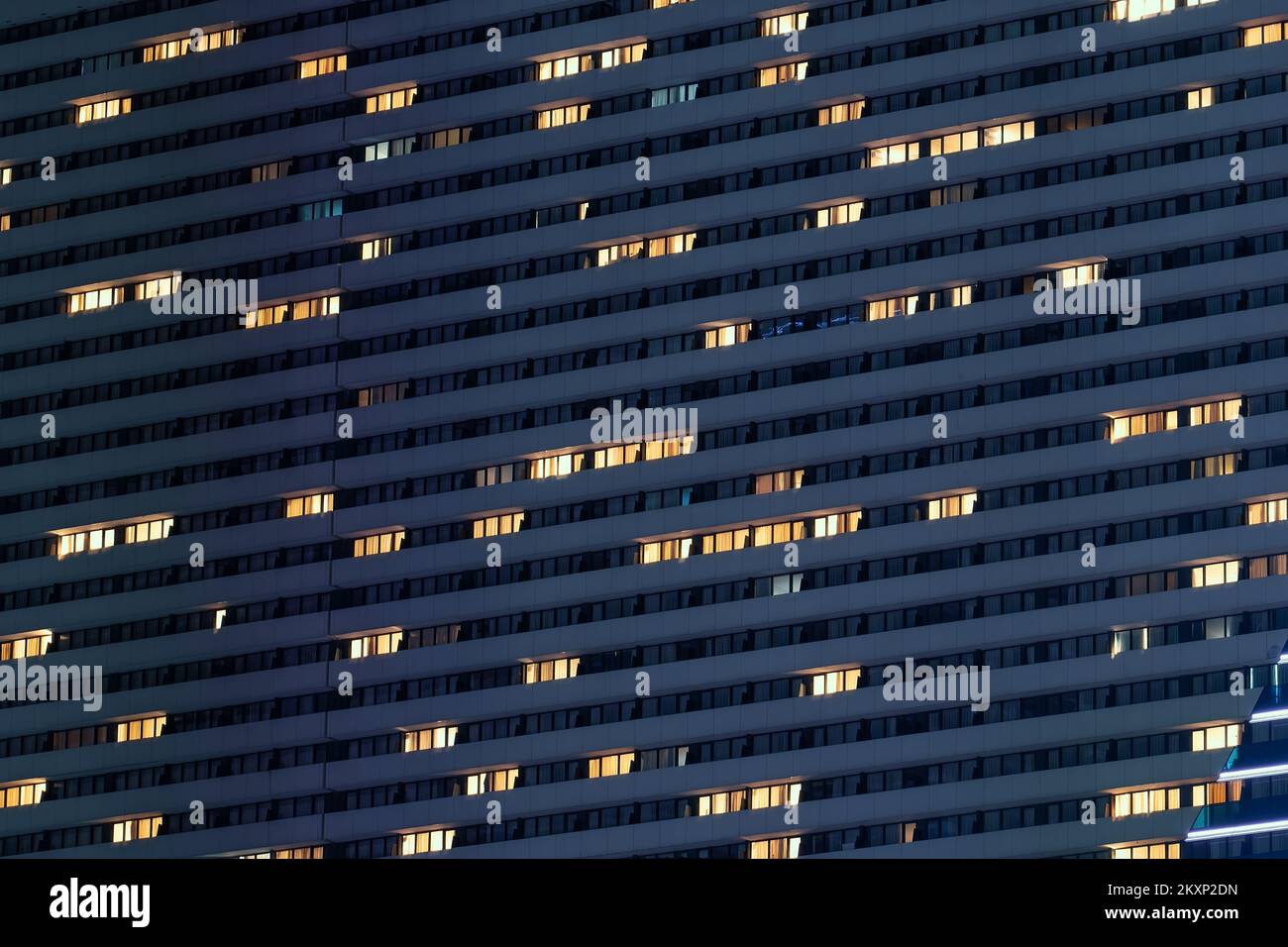 Night facade of high modern building with many illuminated windows. Stock Photo