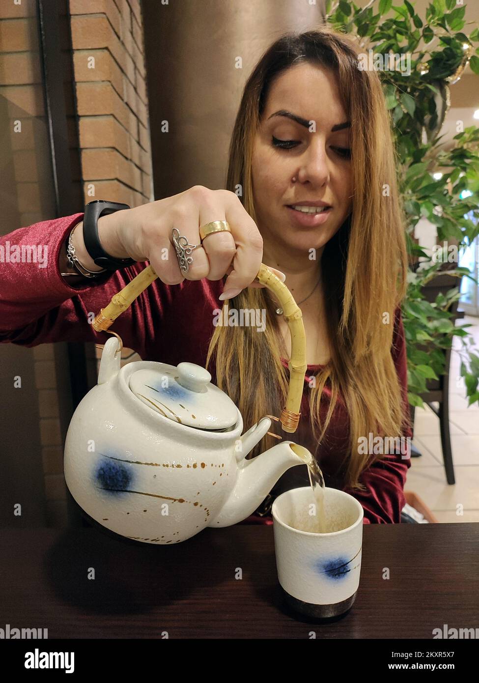 young caucasian geisha handmaid pours herself chai tea with teapot in