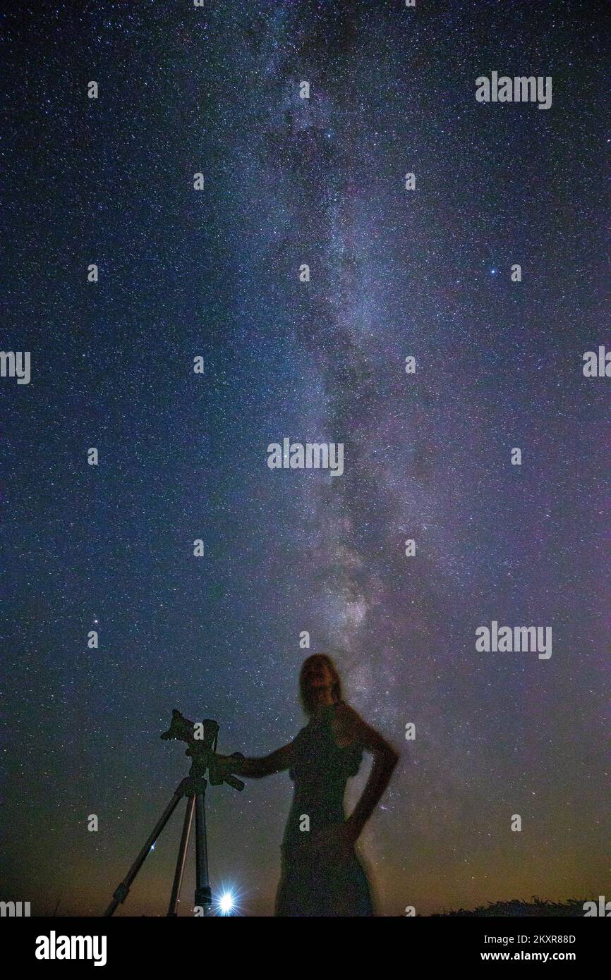 A woman with a camera observes Perseids near the Rt Marlera lighthouse, near Pula, Croatia on ...