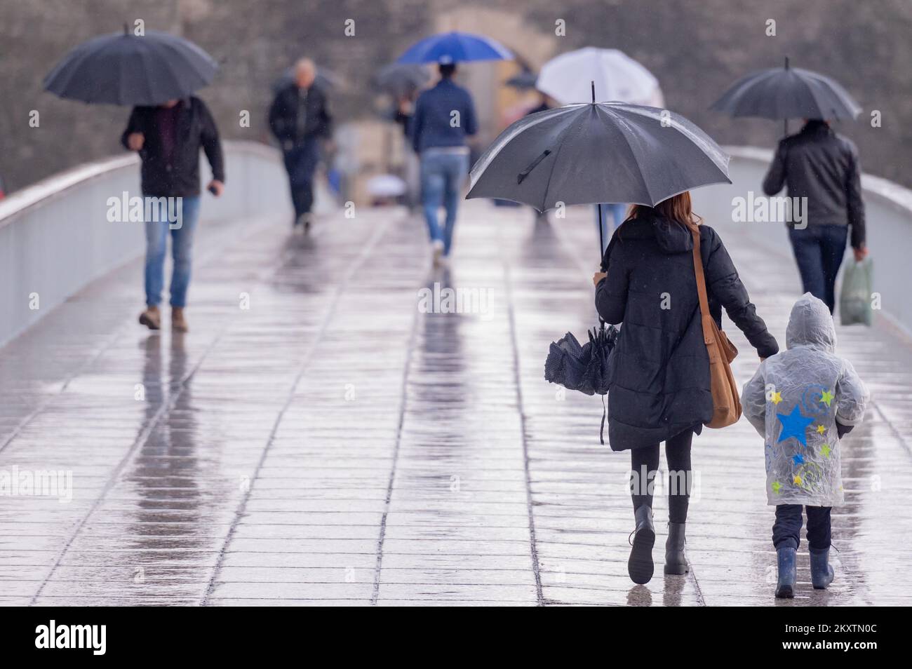 A people holding umbrellas are seen crossing City bridge Zadar in Zadar