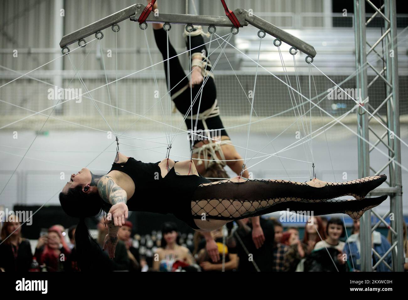 A woman is pulled into the air by hooks inserted directly into her skin