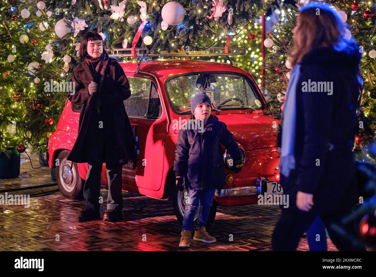 People taking photos by the little red Zastava 750 car, populary know as Fico with mounted giant Christmas tree on the roof during Advent time in Zagreb, Croatia on 01. December, 2021. Photo: Tomislav Miletic/PIXSELL Stock Photo