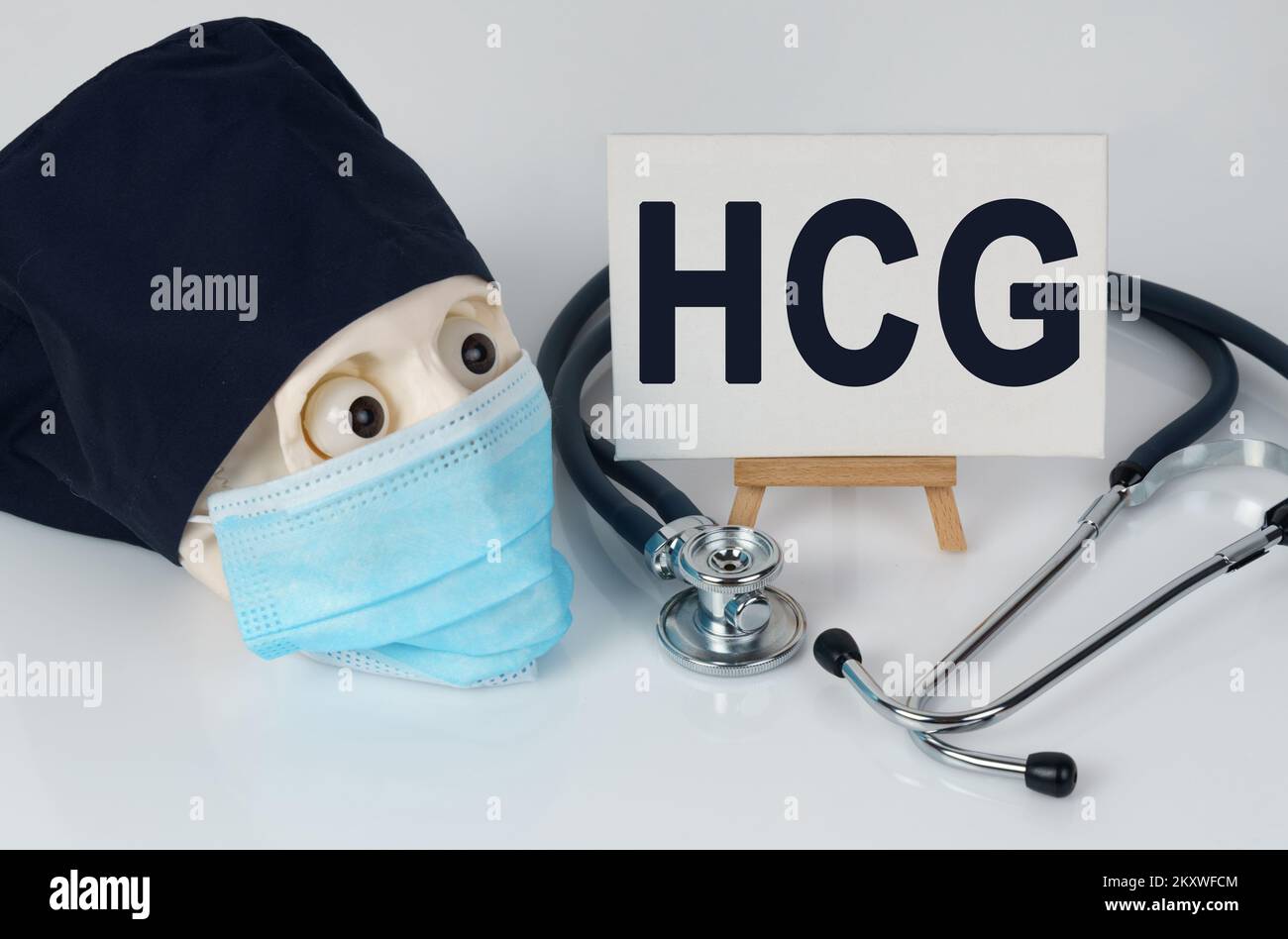 Medicine and health concept. On the table lies a skull in a mask and a cap, a stethoscope and an easel with a canvas on which it is written - HCG Stock Photo