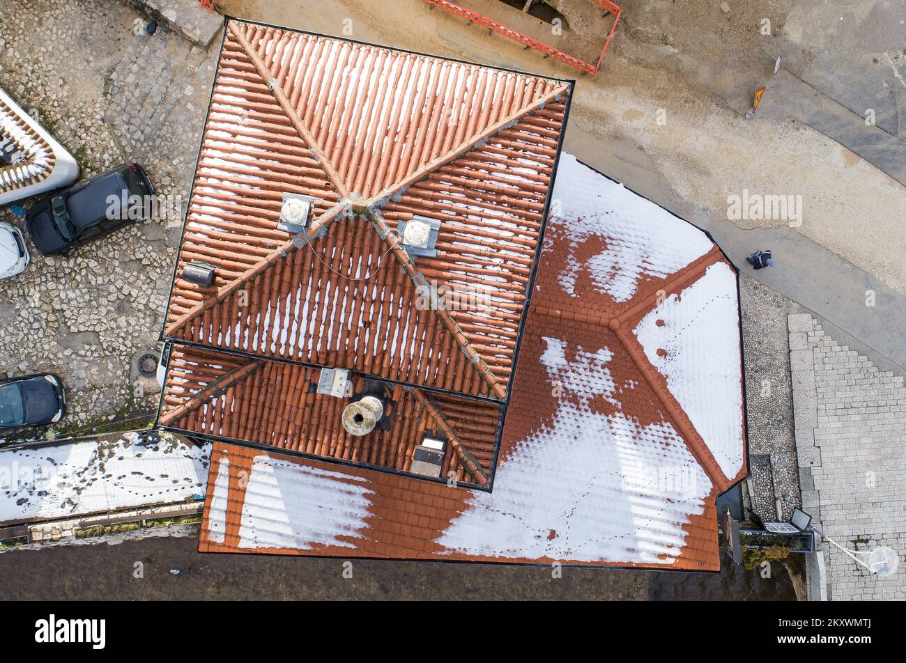 A picture taken by a drone shows Inat house (Spite house). When the location of the construction of the City Hall in Sarajevo was determined, the Austro-Hungarian authorities decided that the construction required the demolition of two restaurants and one house. The owner of the house did not allow it to be demolished for any reason. So, after long negotiations, he asked to be paid in ducats and to move his house to the other side of the coast, brick by brick. They did it and it has been called Inat House (Spite House) ever since. Today it houses a famous restaurant., in Sarajevo, Bosnia and H Stock Photo