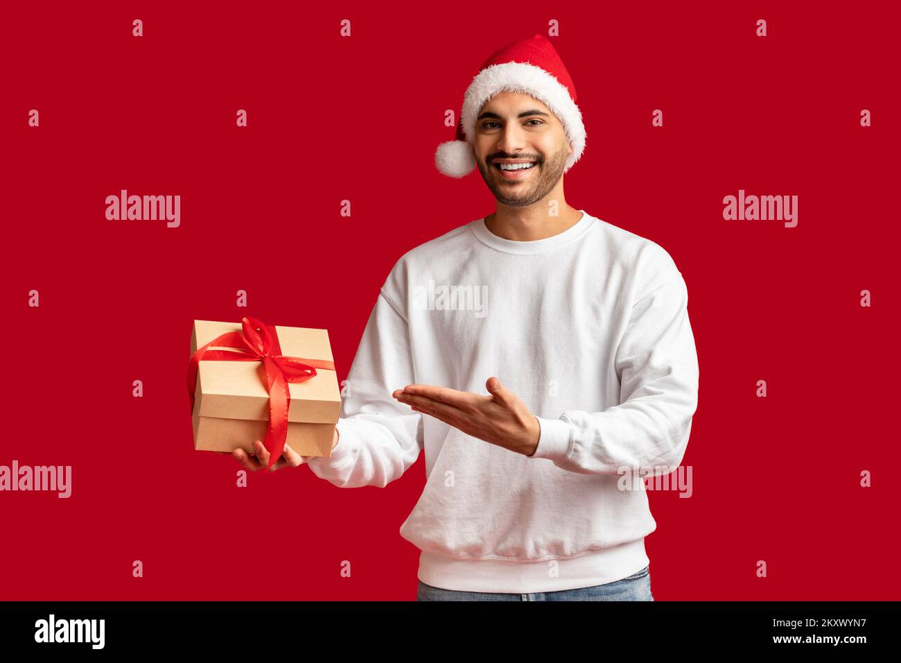 Xmas Offer. Handsome Arab Man In Santa Hat Pointing At Gift Box Stock Photo