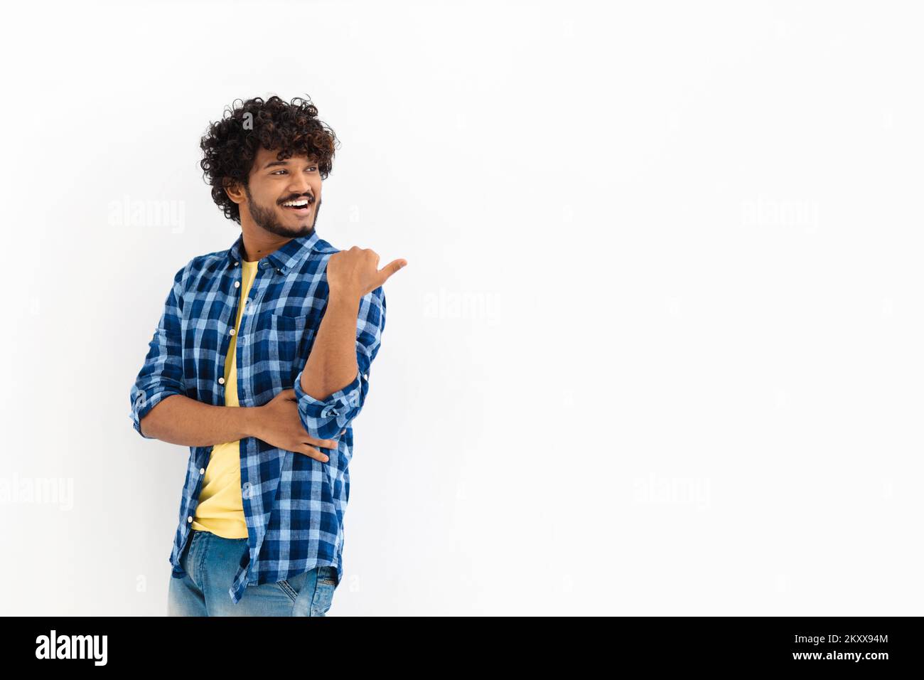 Young Asian man with curly hair and casual stylish clothes smiling with his finger pointing on a white background Stock Photo