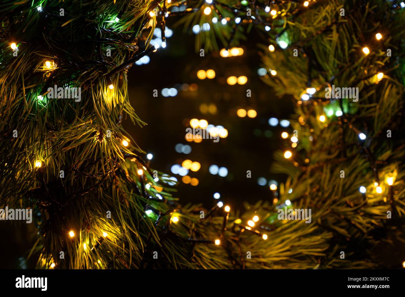 New Year 2023. Christmas beautiful lights bokeh on gold warm background. Defocused Lights on a Tree Background. Christmas tree toys. Golden abstract b Stock Photo