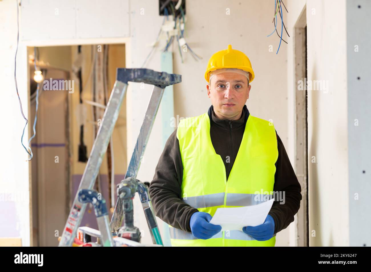 Male contractor looking at room and determining scope of building work ...
