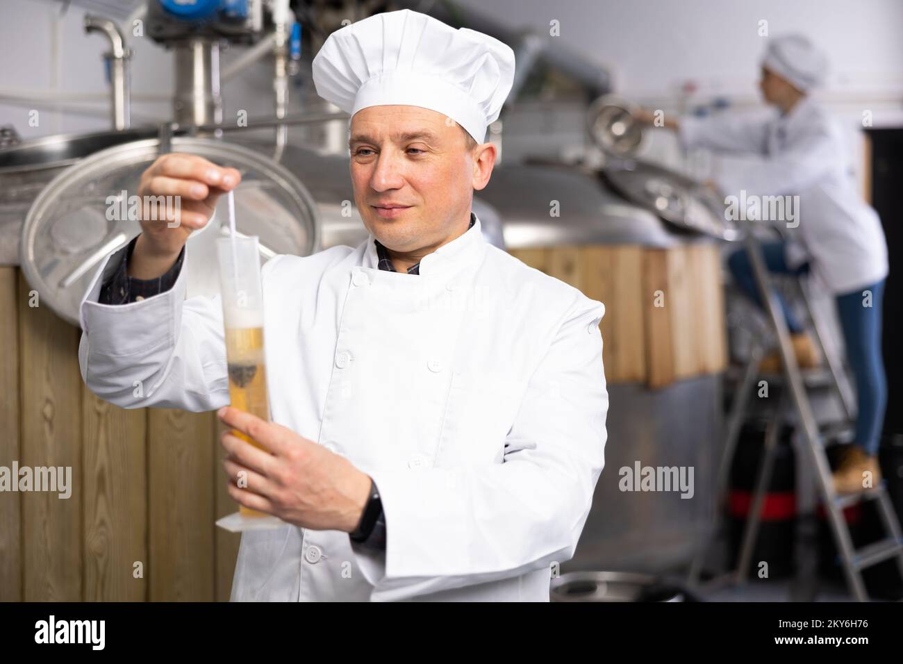 Man brewmaster measuring beer with alcoholometer Stock Photo