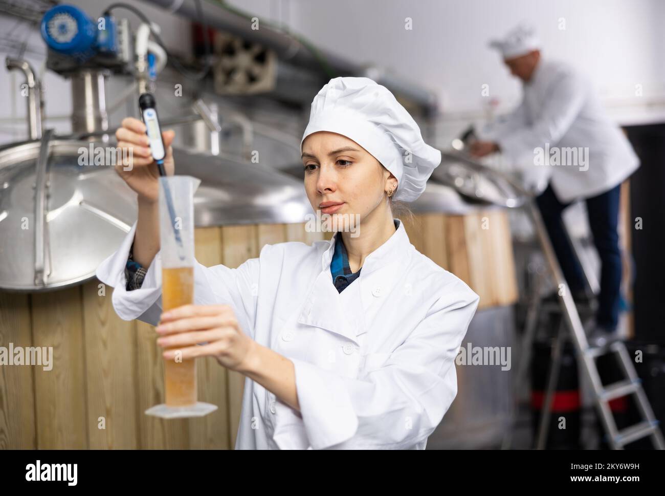 Female brewer using digital hydrometer for measuring beer density Stock
