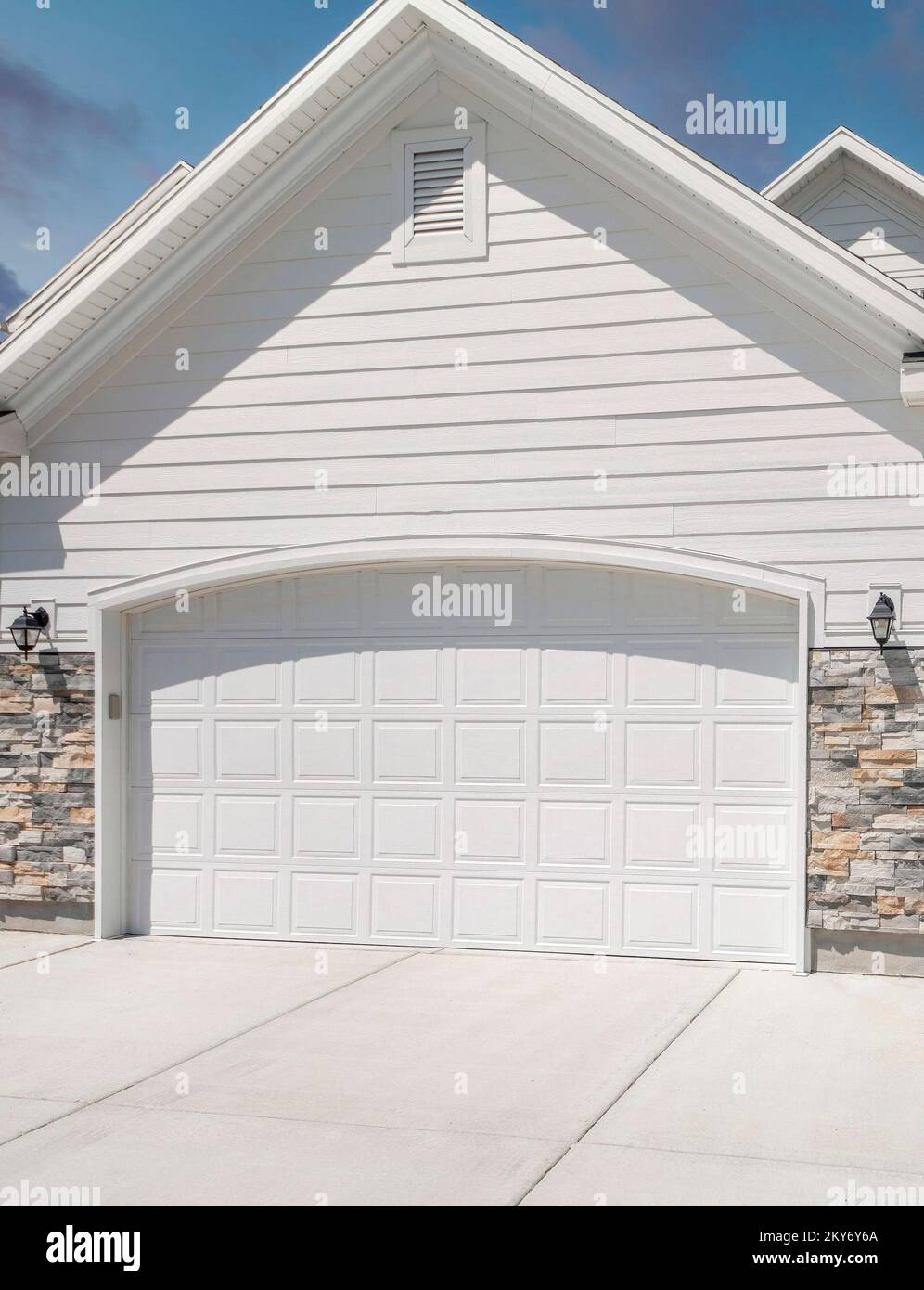 Vertical Puffy clouds at sunset Three car garage exterior with two