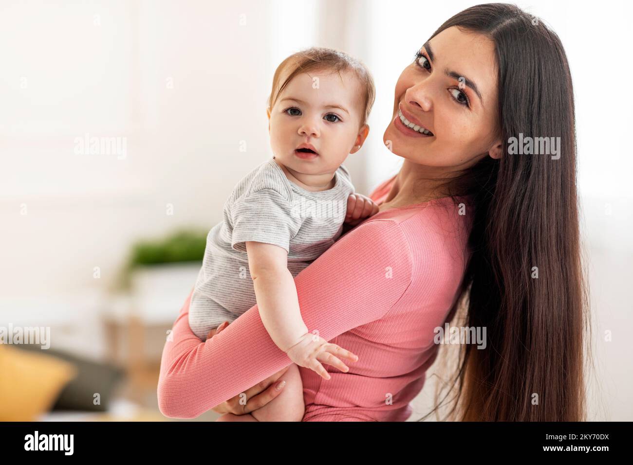 Happiness of motherhood. Portrait of happy mother with cute little baby on her hands looking at camera, copy space Stock Photo