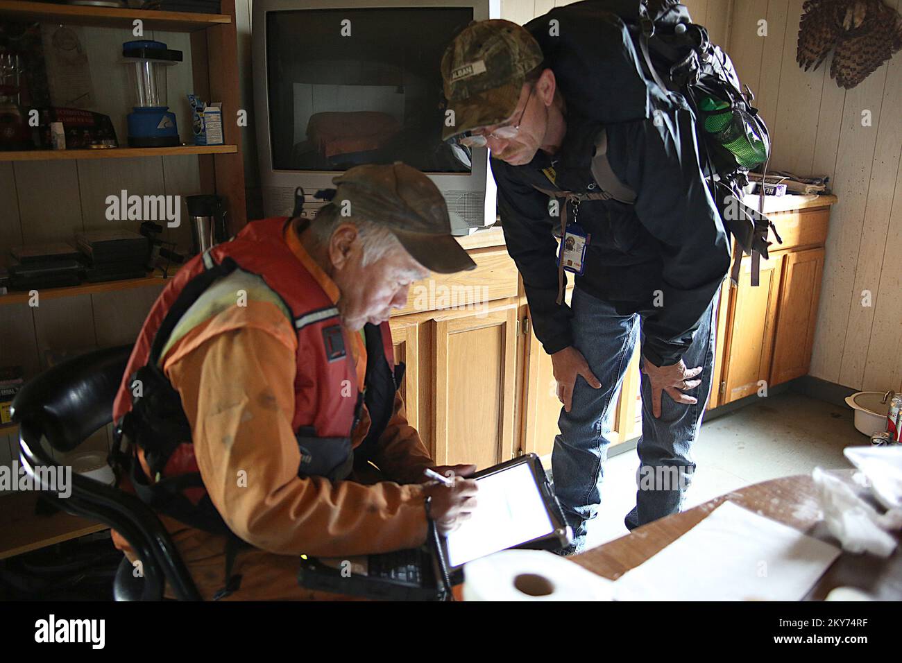 Hughes, Alaska, July 7, 2013   FEMA inspector Marty Williams is working with disaster survivor Ralph Williams by entering his damage data points with innovative tools like advanced field computers and software. Individuals and business owners who sustained losses in the designated area can begin applying for assistance by registering at www.disasterassistance.gov or by calling 1-800-621-FEMA (3362). Adam Dubrowa/ FEMA.. Photographs Relating to Disasters and Emergency Management Programs, Activities, and Officials Stock Photo