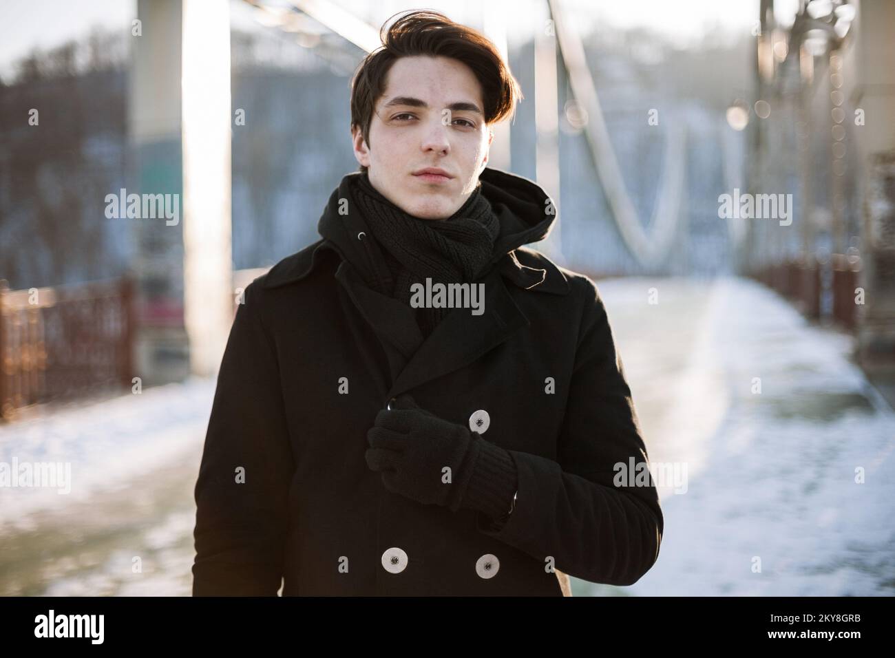 Portrait of a handsome hipster guy standing on the bridge looking at camera Stock Photo