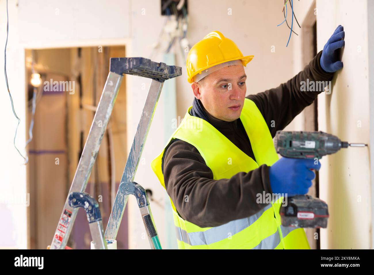 Male contractor holding electric perforator ready for construction works indoors Stock Photo