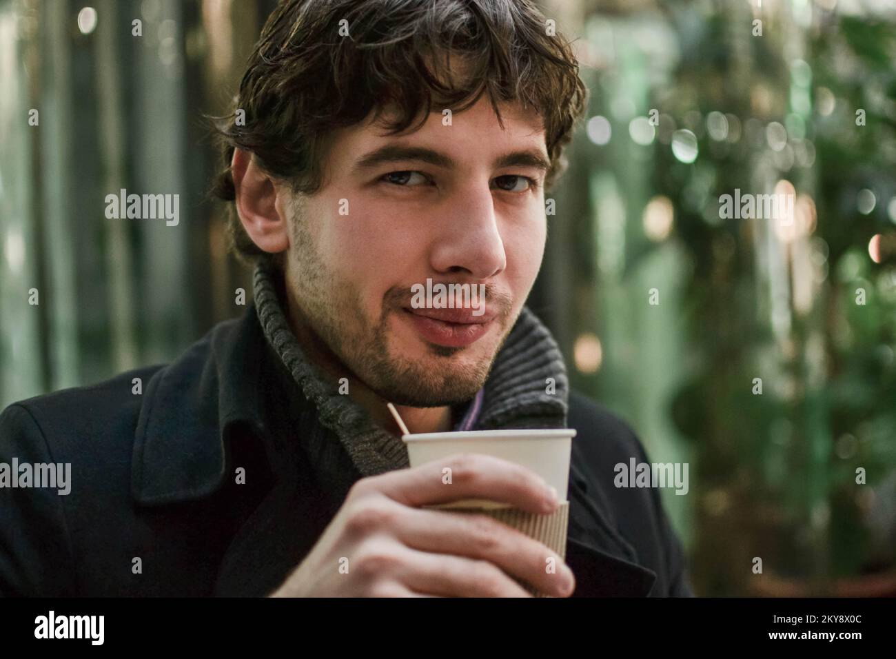 Young handsome man in coat with coffee looking at camera Stock Photo