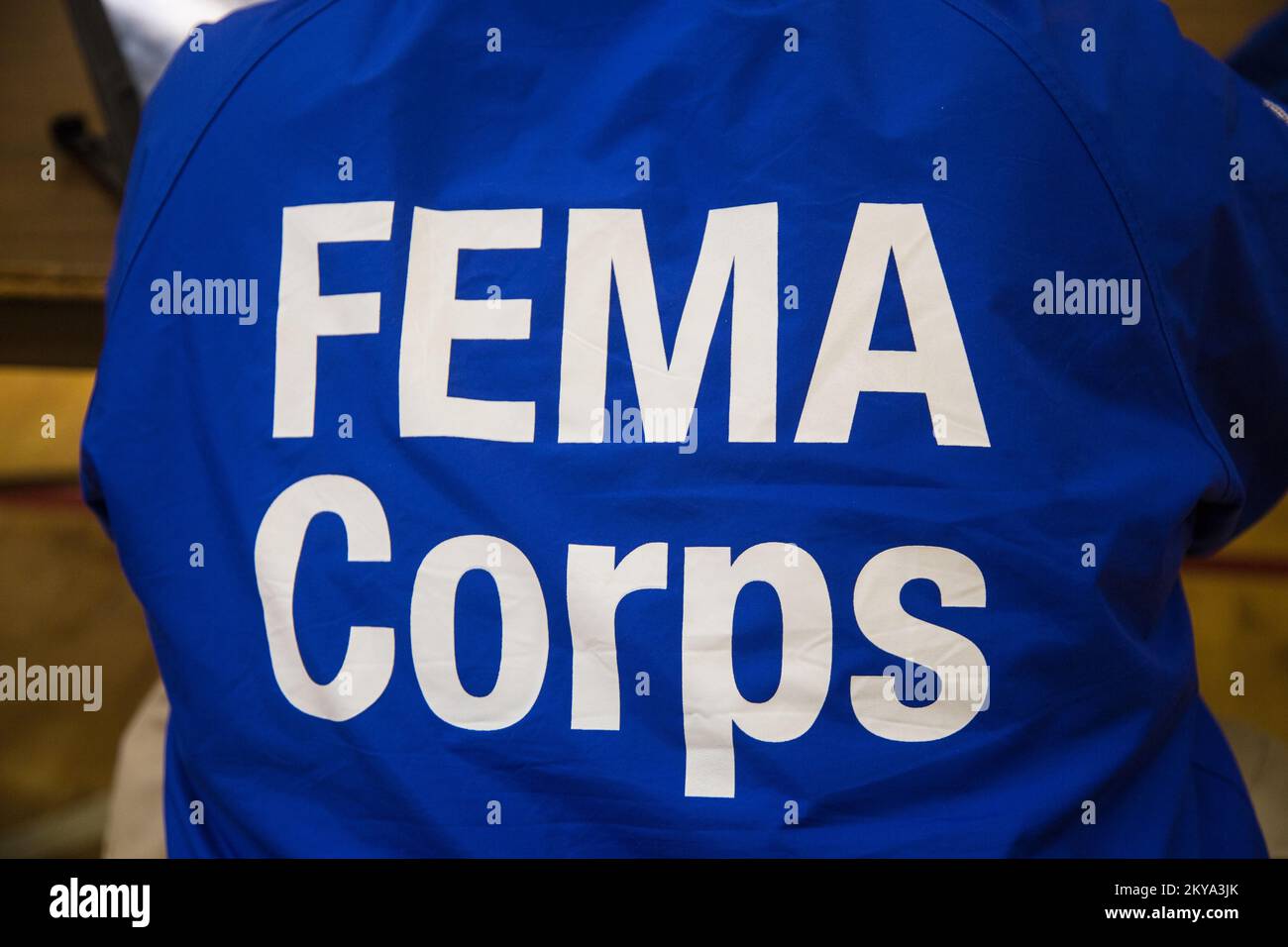 Highland Park, MI, October 4, 2014 - The back of the jacket of Forrest Evans, FEMA Corps Spruce 2 DSA Specialist, as he assists disaster survivor Jolita Cotton at a Recovery Support Site (RSS) in the gymnasium of the Detroit Rescue Mission Community Center in Highland Park, Michigan after the Detroit metropolitan counties of Oakland, Wayne and Macomb were adversely impacted by severe storms and flooding on August 11-13, 2014. FEMA Supports local and state governments and tribal entities in their efforts to recover from natural disasters. Michigan Severe Storms and Flooding. Photographs Relatin Stock Photo