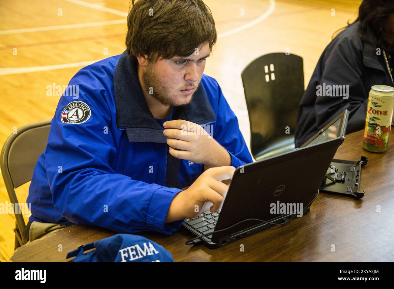 Highland Park, MI, October 4, 2014 - Forrest Evans, FEMA Corps Spruce 2 DSA Specialist, checks his computer as he assists disaster survivor Jolita Cotton at a Recovery Support Site (RSS) in the gymnasium of the Detroit Rescue Mission Community Center in Highland Park, Michigan after the Detroit metropolitan counties of Oakland, Wayne and Macomb were adversely impacted by severe storms and flooding on August 11-13, 2014. FEMA Supports local and state governments and tribal entities in their efforts to recover from natural disasters. Michigan Severe Storms and Flooding. Photographs Relating to D Stock Photo