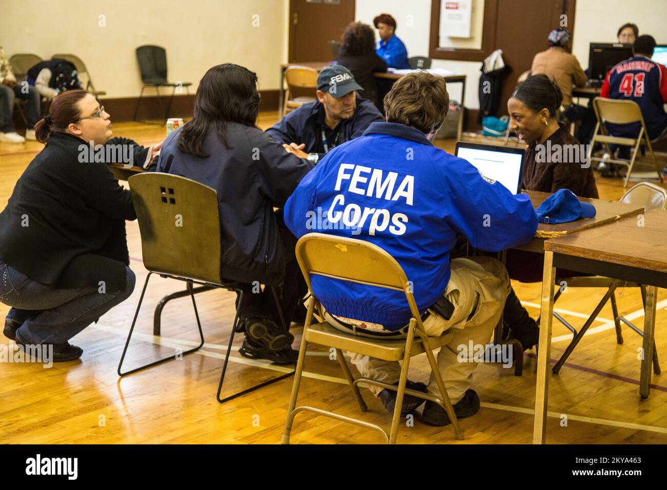Highland Park, MI, October 4, 2014 - Dani Carwile (far left, squatting), NPSC DSA Specialist, Cheryl Catching's (left, seated), FEMA Disaster Survivor Assistance Manager, Javier R. Ortiz-Quiles (center), FEMA DSAT Specialist, Forrest Evans (right, blue FEAM Corps jacket), FEMA Corps Spruce 2 DSA Specialist, assist disaster survivor Jolita Cotton (far right, seated) at a Recovery Support Site (RSS) in the gymnasium of the Detroit Rescue Mission Community Center in Highland Park, Michigan after the Detroit metropolitan counties of Oakland, Wayne and Macomb were adversely impacted by severe storm Stock Photo