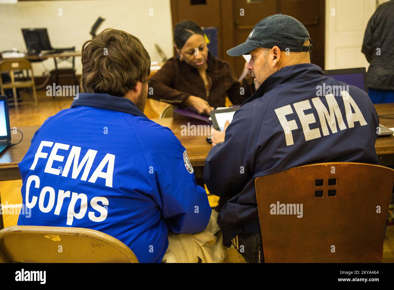 Highland Park, MI, October 4, 2014 - Forrest Evans (left), FEMA Corps Spruce 2 DSA Specialist, and Javier R. Ortiz-Quiles (right), FEMA Disaster Assistance Specialist, assist disaster survivor Jolita Cotton (center) at a Recovery Support Site (RSS) in the gymnasium of the Detroit Rescue Mission Community Center in Highland Park, Michigan after the Detroit metropolitan counties of Oakland, Wayne and Macomb were adversely impacted by severe storms and flooding on August 11-13, 2014. FEMA Supports local and state governments and tribal entities in their efforts to recover from natural disasters. Stock Photo