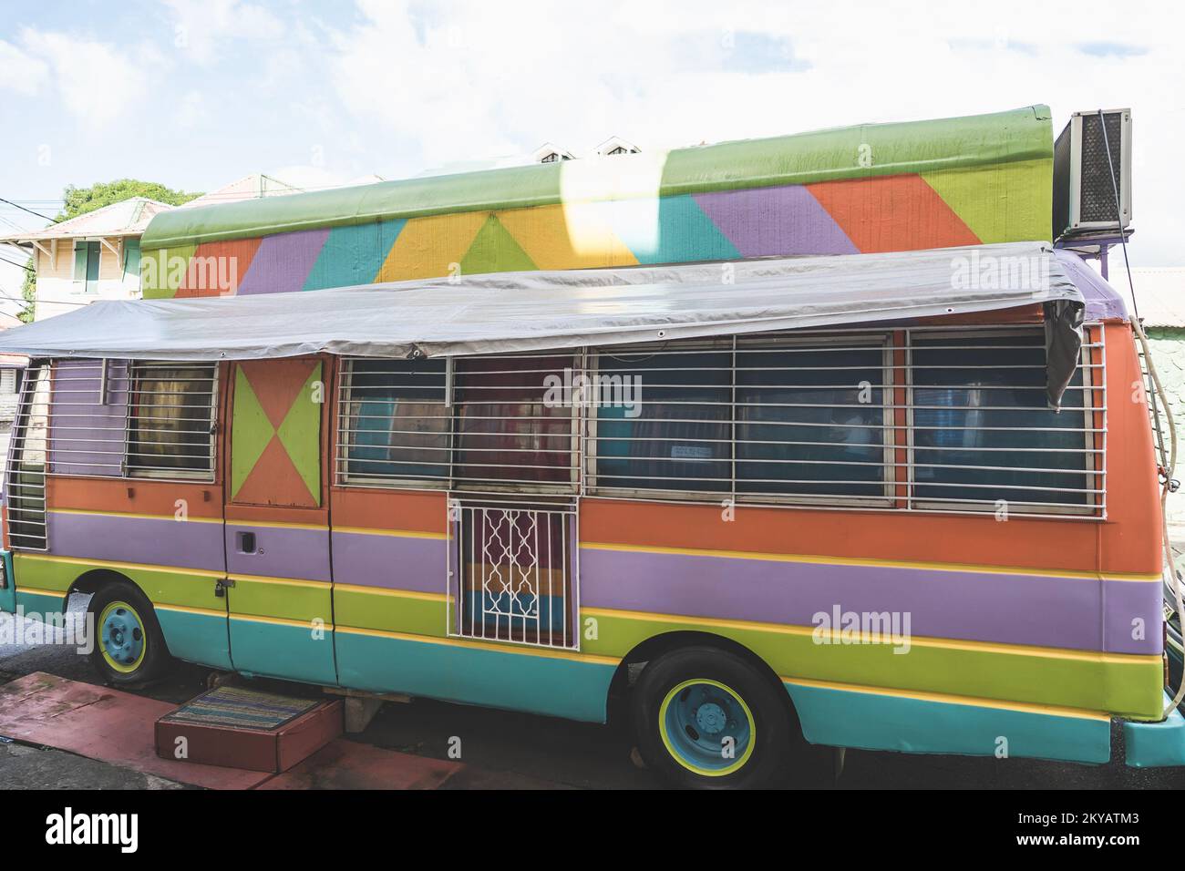 Closed colorful food truck on a street painted in stripes of colors with window bars Stock Photo
