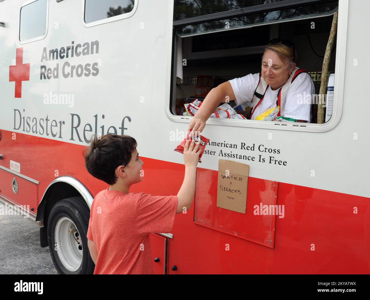 Houston, TX, June 6, 2015   Red Cross volunteer Glenda Dawson, right, gives a snack to Ben Rotenberg from a Red Cross distribution truck that is at the Mobile Disaster Registration Intake Center. Residents are encouraged to register with FEMA at 1-800-621-FEMA (3362), TTY 1-800-462-7585 or at www.disastperassistance.gov. Jocelyn. Houston, TX, June 6, 2015 -- Red Cross volunteer Glenda Dawson, right, gives a snack to Ben Rotenberg from a Red Cross distribution truck that is at the Mobile Disaster Registration Intake Center.Residents are encouraged to register with FEMA at 1-800-621-FEMA (3362), Stock Photo