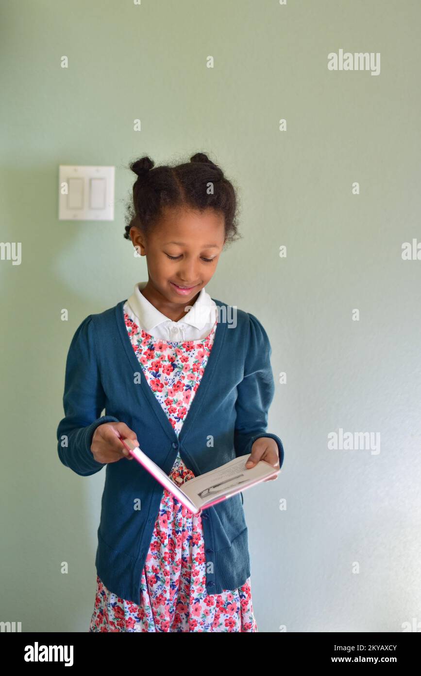 little girl standing up reading a book for school Stock Photo