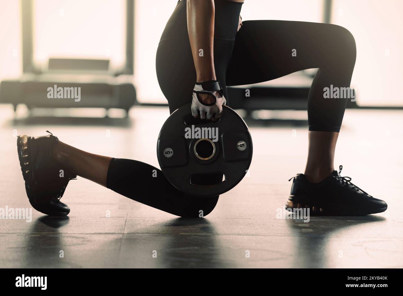 Sporty woman doing workout with weight plate at the gym. Stock Photo