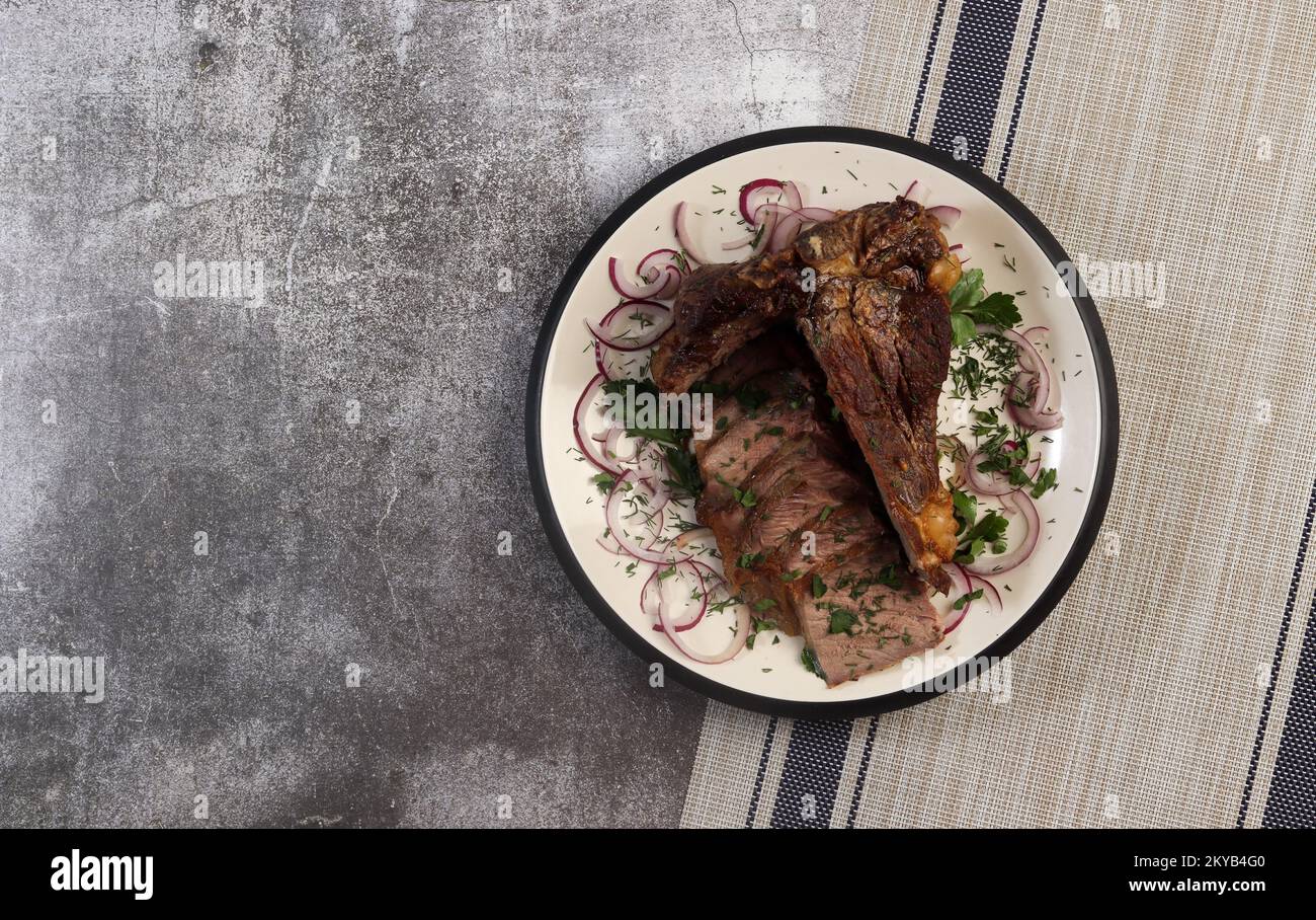 Sliced roast Tbone beef steak and herbs on a round plate on a dark