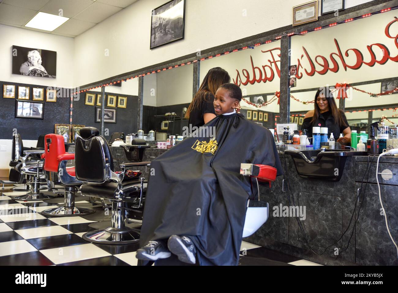 Woman Barber and hairstylist Cutting a young black boy’s hair Stock Photo