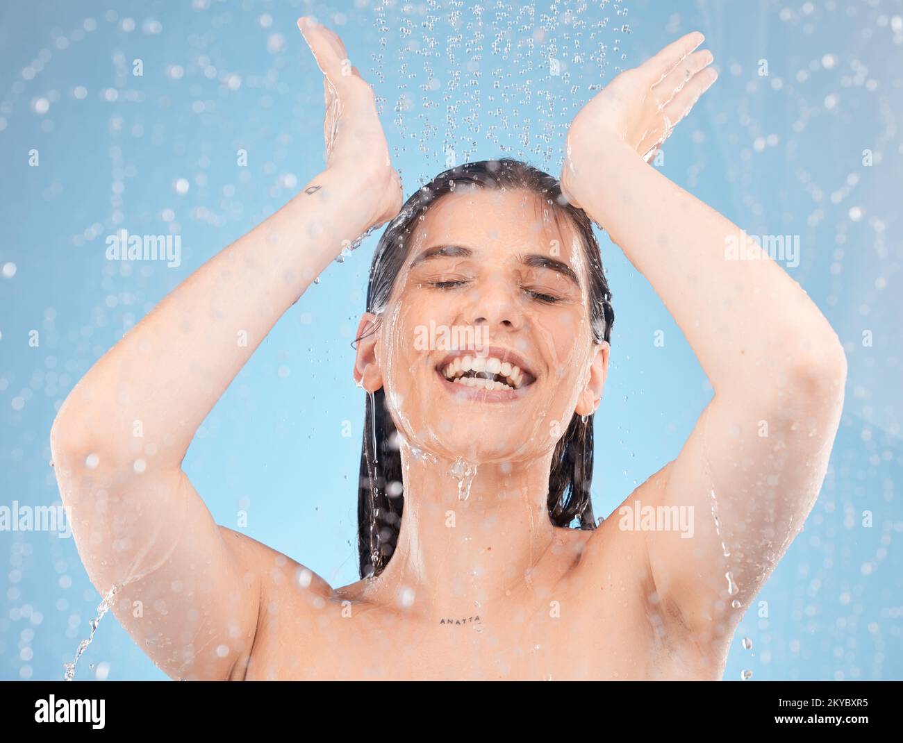 Woman, showering and water splash on blue background in studio for
