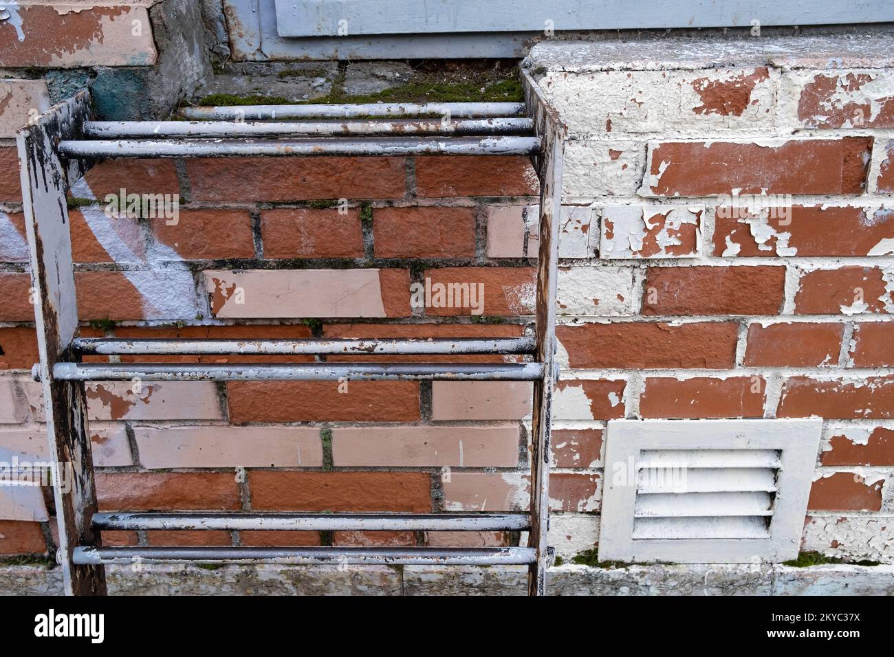 Details of a brick building with peeling paint, with a metal staircase