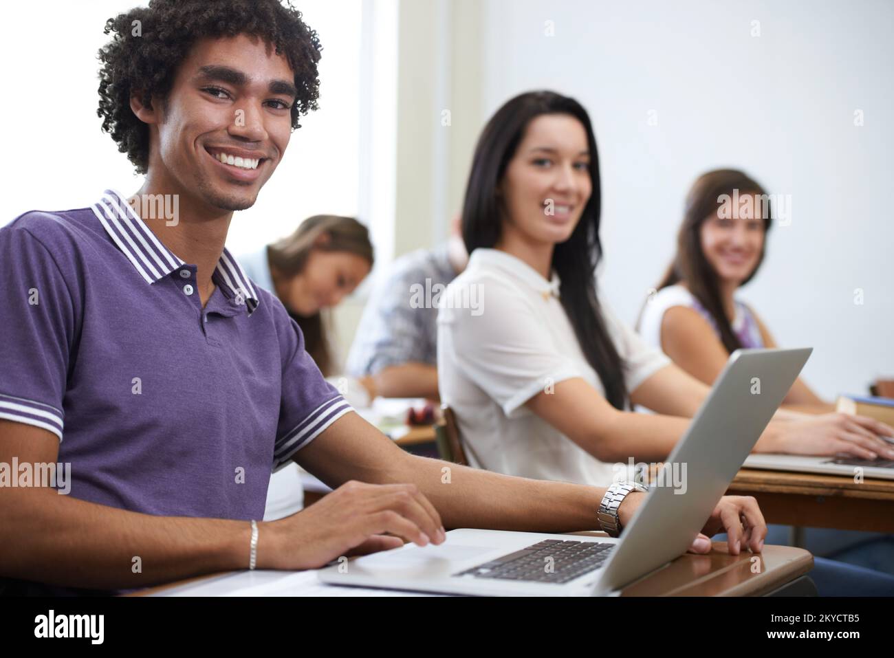 Future software developers...Portrait of a group of smiling university students working on laptops in class. Stock Photo