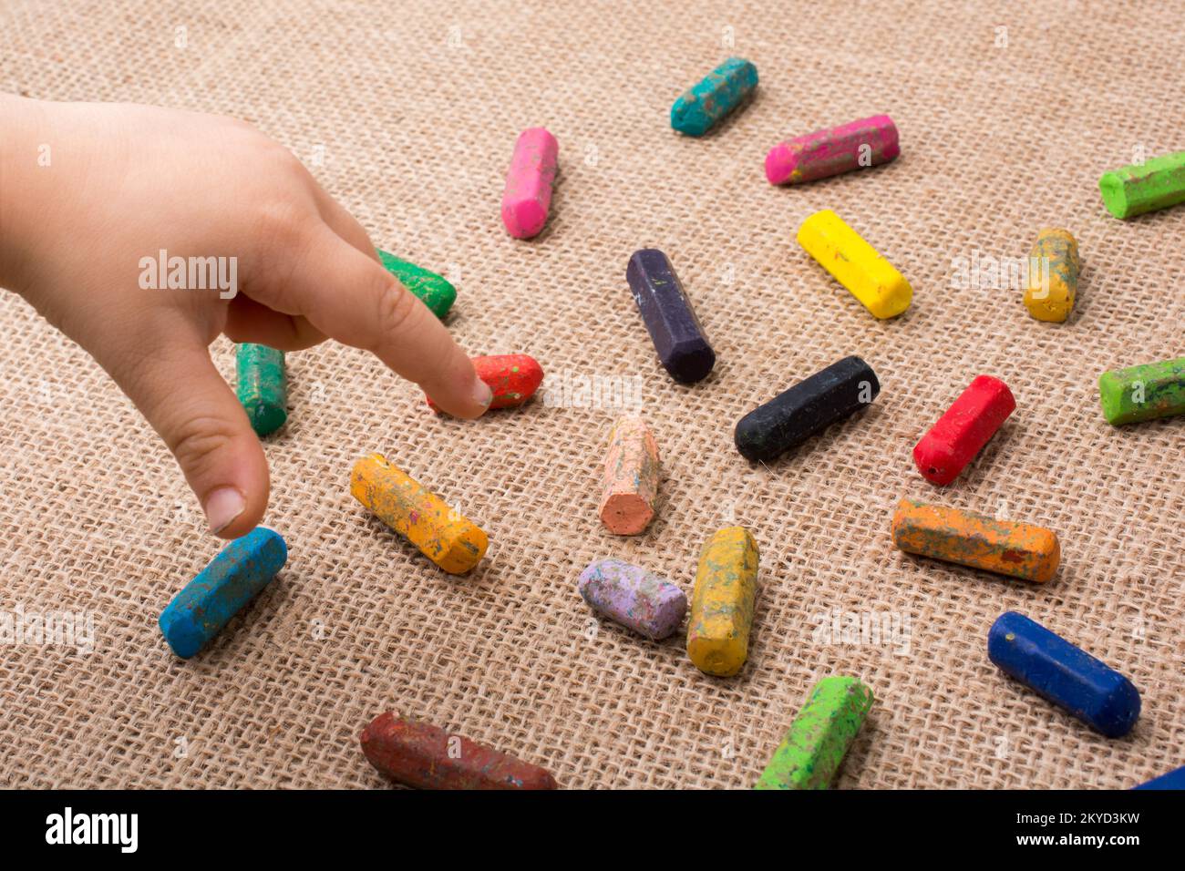 Used color crayons and a toddlers hand pointing Stock Photo Alamy