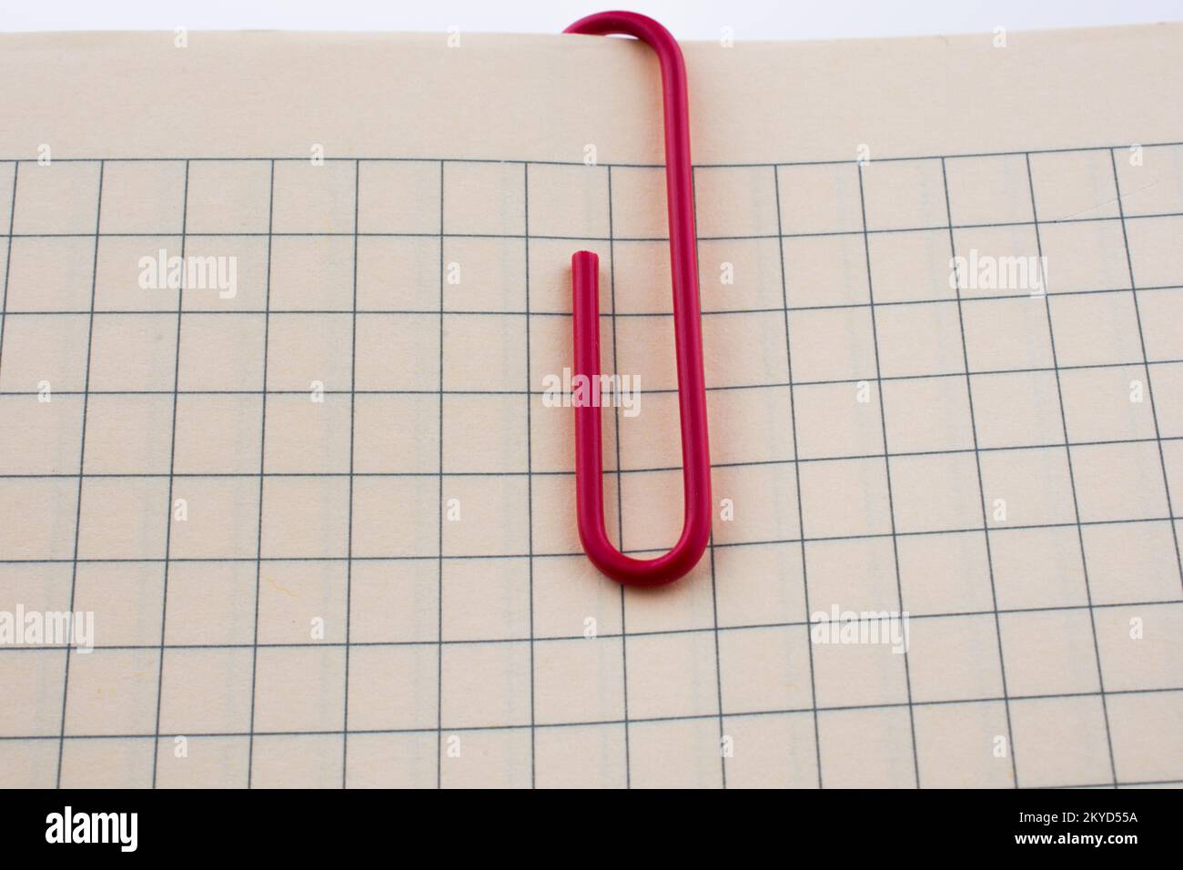 Colored paper clip on a checked notebook page Stock Photo