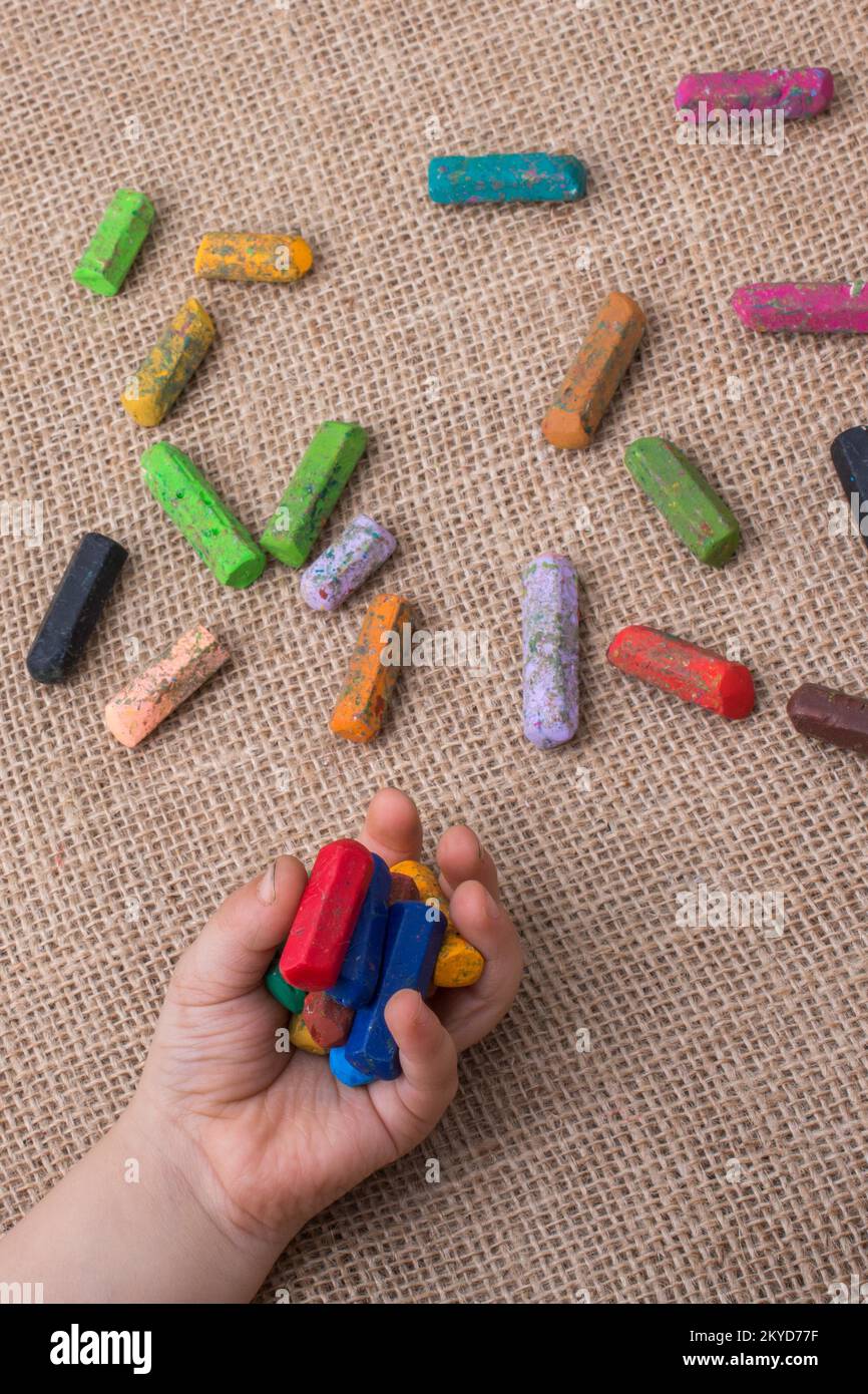 Used color crayons and a toddlers hand holding some Stock Photo Alamy