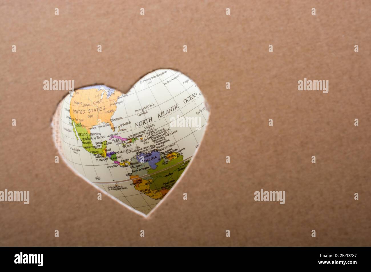 Globe seen through the heart shape hole on paper Stock Photo
