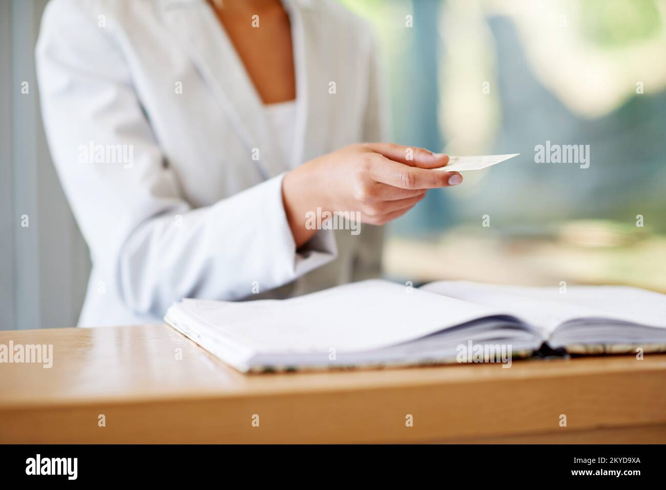 Heres my card. a woman preparing to pay with a credit card at a reception desk. Stock Photo