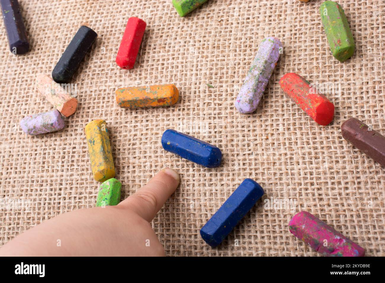 Used color crayons and a toddlers hand pointing Stock Photo Alamy