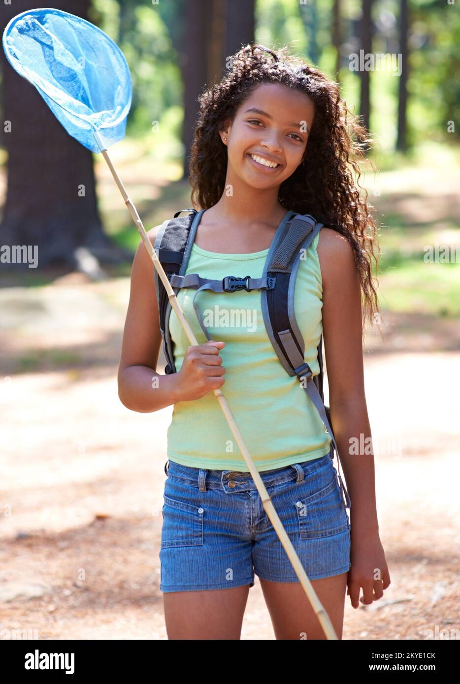 Catching butterflies. A young girl with a butterfly net in a forest. Stock Photo