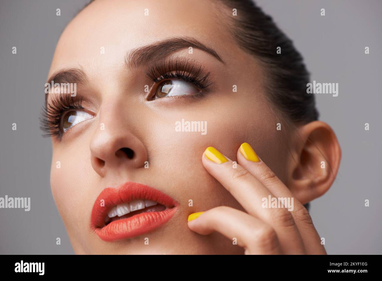 Beauty defined by color. An attractive young woman wearing red lipstick and colourful nail polish. Stock Photo