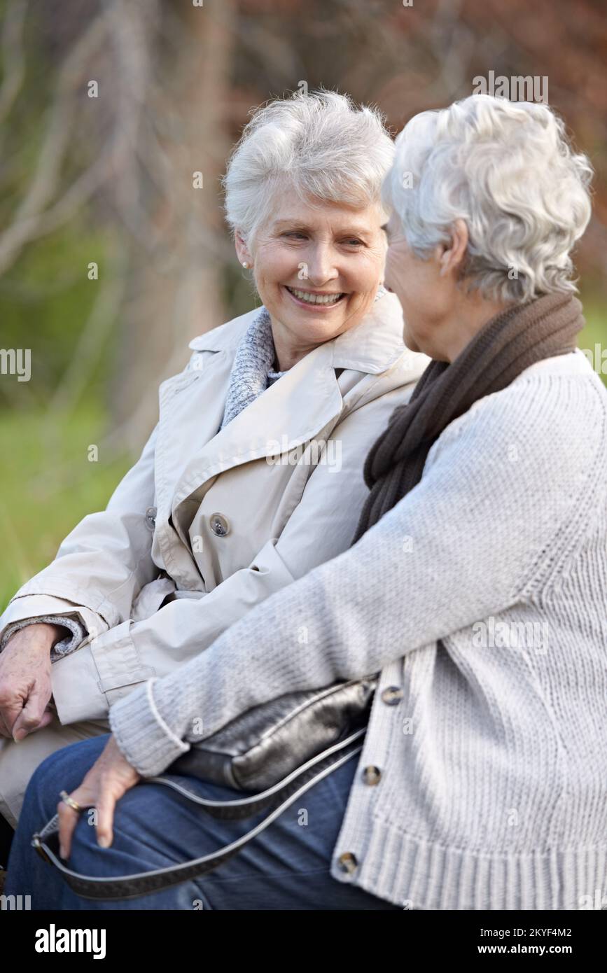 Catching up with an old friend. Two smiling senior women sitting together outdoors. Stock Photo